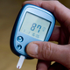 A person measuring their blood sugar level through a finger prick test.